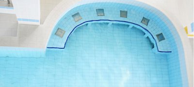 Jasnoniebieski basen z p&oacute;łokrągłą wnęką i podwodnymi dyszami przy brzegu