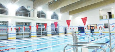 Kryty basen sportowy z torami pływackimi, chorągiewkami i jasnym oświetleniem
