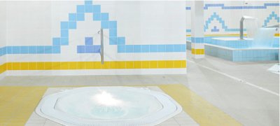 Wanna z hydromasażem w jasnym wnętrzu basenowym z niebiesko-ż&oacute;łtymi płytkami