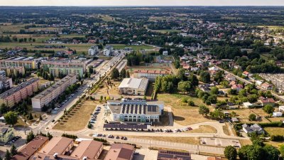 Panorama miasta z osiedlami, szkołą, parkingami i terenami zielonymi widziana z lotu ptaka
