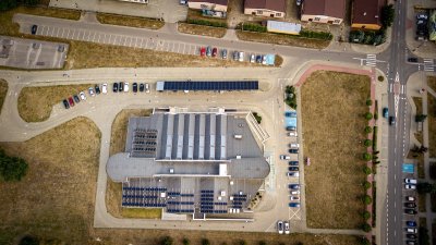 Budynek z panelami fotowoltaicznymi i parkingiem widziany z lotu ptaka