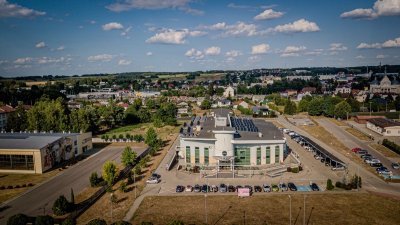 Panorama miasta z centrum kultury, parkingiem, zabudową i kościołem pod błękitnym niebem z chmurami