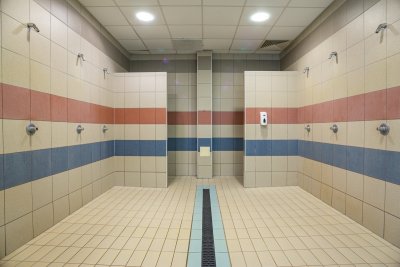 Wnętrze publicznych pryszniców z kafelkami, kabinami, natryskami i odpływem liniowym