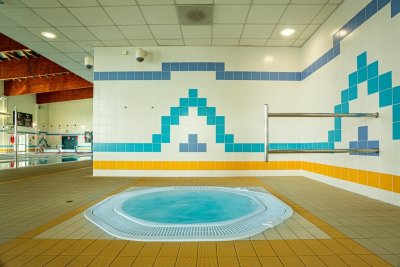 Jacuzzi na krytej pływalni z kafelkami w turkusowe i żółte wzory