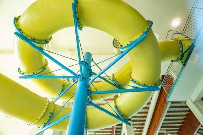 Żółta spiralna zjeżdżalnia wodna z niebieską konstrukcją wewnątrz budynku