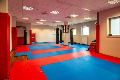 Sala treningowa ze sportowymi matami, workami bokserskimi i drabinkami do ćwiczeń