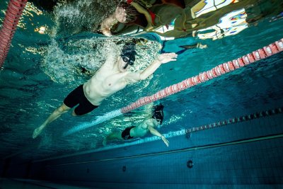 Pływacy w okularach płyną pod wodą na basenie sportowym między torami pływackimi