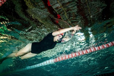 Pływaczka w czepku i okularach płynie pod wodą kraulem w basenie sportowym