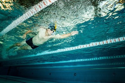 Pływak z fajką i okularami płynie pod wodą w basenie sportowym między torami