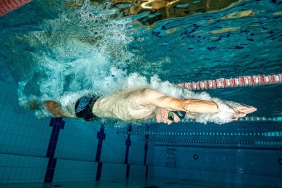 Pływak pod wodą płynie kraulem w basenie sportowym przy linie toru