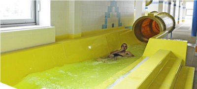 Osoba relaksuje się w basenie z hydromasażem obok zjeżdżalni w aquaparku
